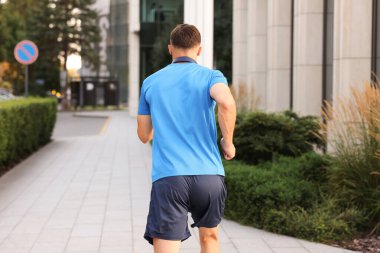 Spor giyimli bir adam dışarıda koşuyor.