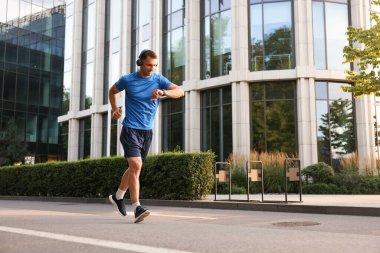 Adam açık havada koşarken fitness izleyicisini kontrol ediyor, metin için boşluk