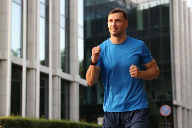 Spor giyimli bir adam açık havada koşuyor. Düşük açılı. Metin için boşluk