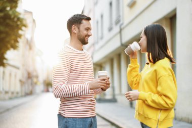 Paket kahve. Şehir caddesinde kağıt bardak içen bir çift.