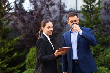 Paket kahve. Açık havada buluşurken kağıt bardak içen bir adam ve iş ortağı, mesaj atmak için yer.
