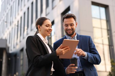 Paket kahve. Açık havada buluşurken kağıt bardak içen bir adam ve iş ortağı. Düşük açı.