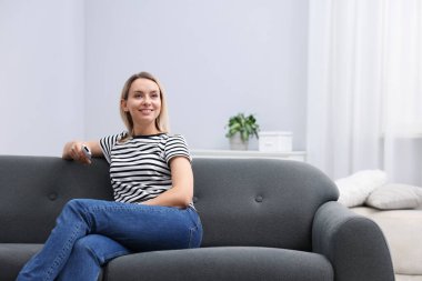 Evdeki kanepede klimalı uzaktan kumandalı bir kadın. Metin için boşluk