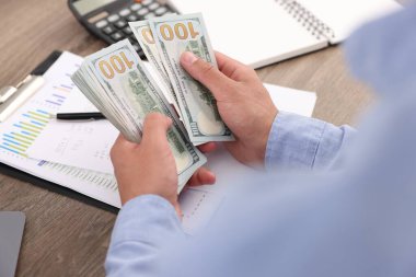 Ahşap masada dolar sayan adam, yakın plan.