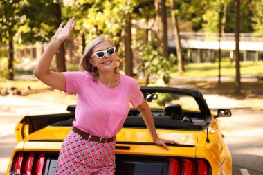 Modern Cabriolet yakınlarında güneş gözlüklü şık bir son sınıf öğrencisi.