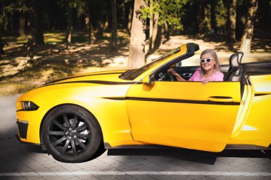 Modern Cabriolet yakınlarında güneş gözlüklü şık bir son sınıf öğrencisi.