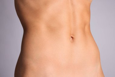 Gri arka planda düz göbekli kadın, yakın plan.