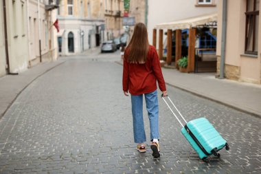 Hoşçakalın. Bagajı olan bir kadın dışarıda yürüyor, arka manzaralı. Metin için boşluk
