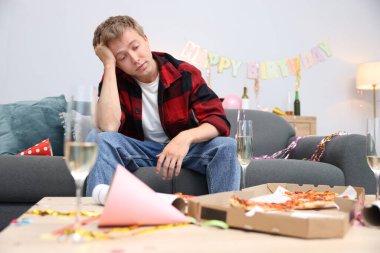 Adam partiden sonra dağınık bir odada kanepede akşamdan kalma.