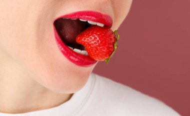 Dudak makyajı yapan güzel bir kadın ve tozlu pembe arka planda çilek, yakın plan. Metin için boşluk