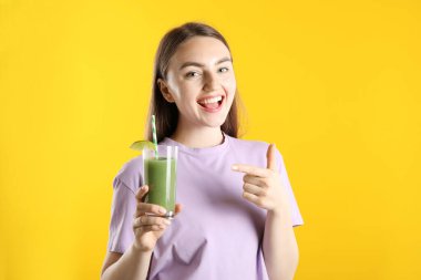 Turuncu arka planda serinletici içkisi ve pipetli kadın