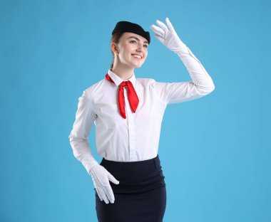 Açık mavi arka planda üniformalı hoş hostes.