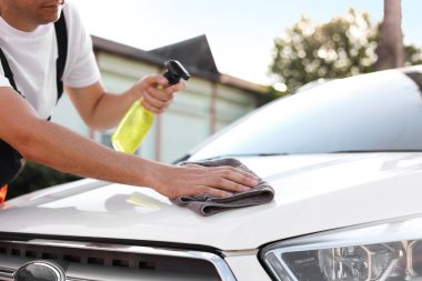 Kaputu gri mikrofiber bez ile silen adam, yakın plan.