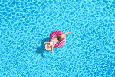 Yüzme havuzunda şişme yüzüklü, genç ve mutlu bir kadın. Yaz tatili