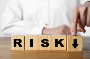 İş riski. Masada okla tahta küpe dokunan kadın, yakın plan.