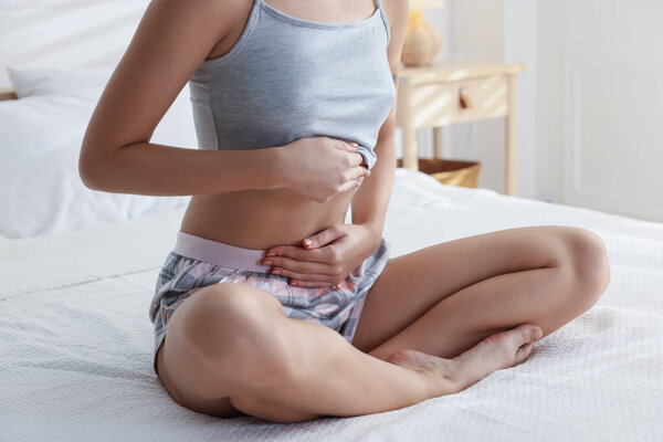 Молодая женщина с плоским животом на кровати дома, крупным планом