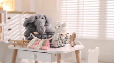 Farklı çocukların oyuncakları beyaz masada, kapalı alanda. Kamera sola hareket ediyor