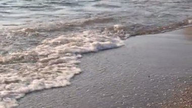 Güzel dalgalı deniz, kumlu sahil ve taşlar, kamera yükseliyor.