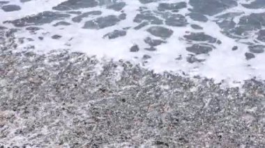 Dalgalı deniz ve çakıl taşlarının güzel manzarası, yakın çekim.
