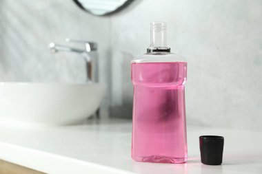 Bottle and cap of mouthwash on white counter in bathroom. Space for text