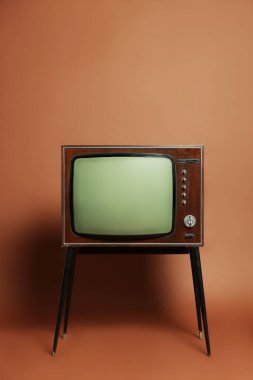 Retro TV set on stand against brown background. Used stuff