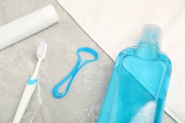 Mouthwash and other oral hygiene products on light marble table, closeup
