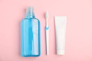 Mouthwash, toothbrush and toothpaste on pink background, flat lay