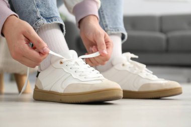 Beyaz spor ayakkabı bağcığı bağlayan kadın, yakın plan.