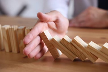 Risk. Tahta masada domino efektini durduran adam, yakın plan.