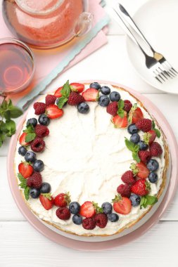 Delicious crepe cake with fresh berries served on white wooden table, flat lay