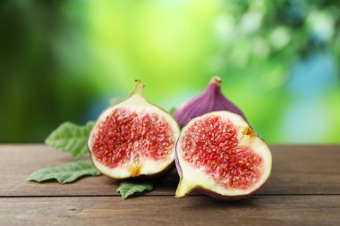 Taze incir ve yeşil yaprak dışarıda, ahşap masada, yakın plan.