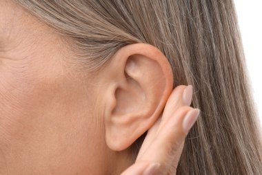 Ses geliyor. Üst düzey kadın beyaz arka planda el ele hareketler gösteriyor, yakın plan.