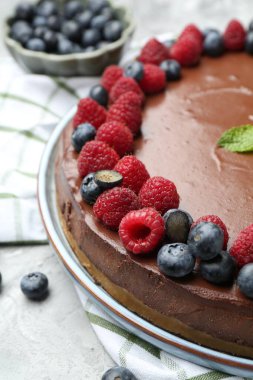 Delicious chocolate cheesecake with berries and mint on grey table, closeup