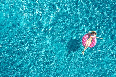 Yüzme havuzunda şişirilebilir yüzüklü genç bir kadın. Yaz tatili