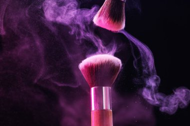 Renkli göz gölgeli makyaj fırçaları siyah arka planda neon ışıkları, yakın plan