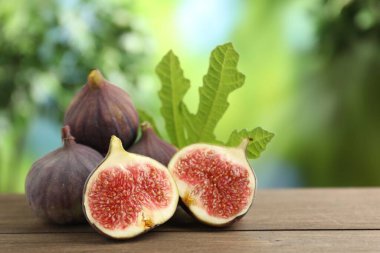 Taze incir ve açık havada, ahşap masada yeşil yaprak, yakın plan. Metin için boşluk