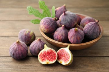 Taze incir ve yeşil yaprak ahşap masada, yakın plan.