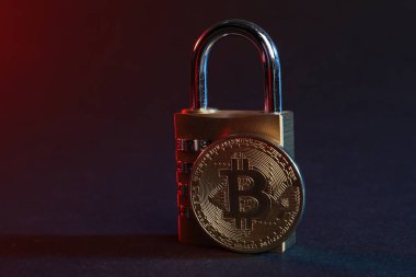 Bitcoin ve asma kilit mavi arkaplanda kırmızı ışıkta, yakın plan