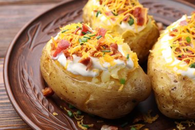 Ekşi kremalı fırında patates, yeşil soğan, ahşap masada peynir ve pastırma, yakın plan.