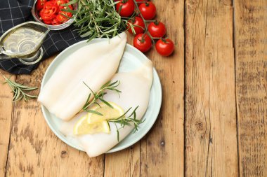 Limon dilimli pişmemiş mürekkep balıkları, ahşap masada biberiye ve baharatlar. Metin için boşluk