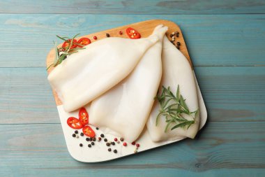 Mavi ahşap masada baharatlı pişmemiş mürekkep balıkları.