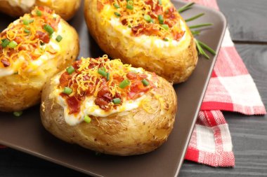 Lezzetli fırında patatesler siyah masada, yakın plan.