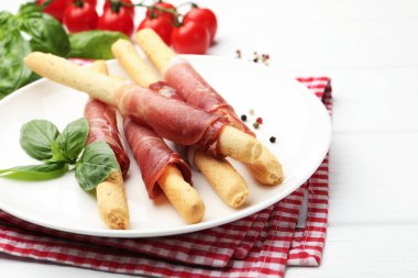 Lezzetli Grissini çubukları prosciutto, biber ve fesleğen ile beyaz ahşap masa, yakın çekim