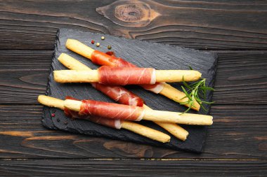 Prosciutto, biber ve ahşap masada biberiye ile nefis Grissini çubukları.