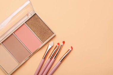 Renkli göz farı paleti, makyaj fırçaları ve bej arka planda aplikatör, düz yatış. Metin için boşluk