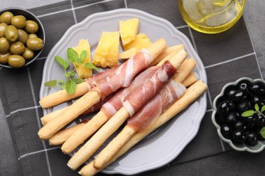 Grissini ekmeği jambonlu, peynirli ve zeytinli gri masada, düz yatıyordu.