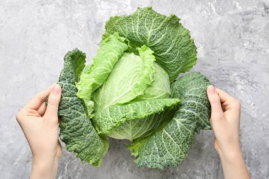 Gri desenli masasında taze Savoy lahanası olan kadın.