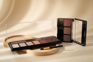 Renkli göz falı paletleri ve bej arka planda makyaj fırçası, gölgeler, yakın plan