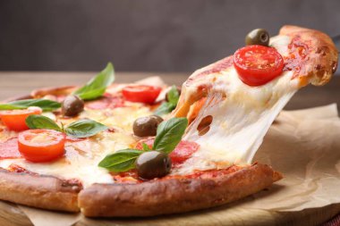 Peynirli, salamlı, domatesli ve zeytinli leziz pizzayı yakın plan.