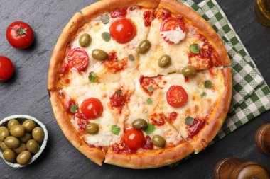 Delicious pizza with cheese, tomatoes and olives on black table, flat lay